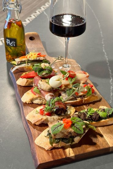 A wooden tray of pincho and wine